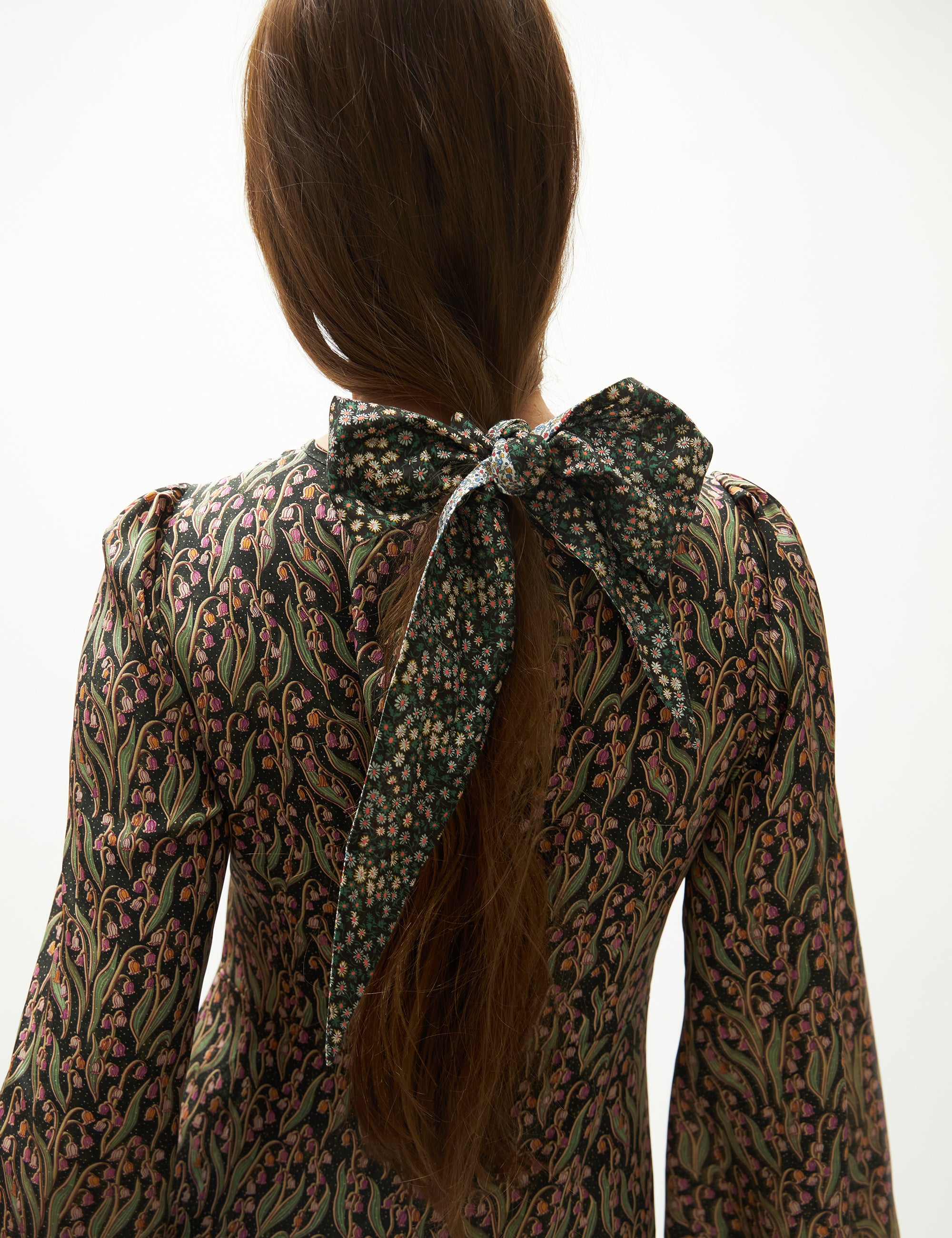 Close-up of a person wearing a floral patterned silk dress with a bow detail