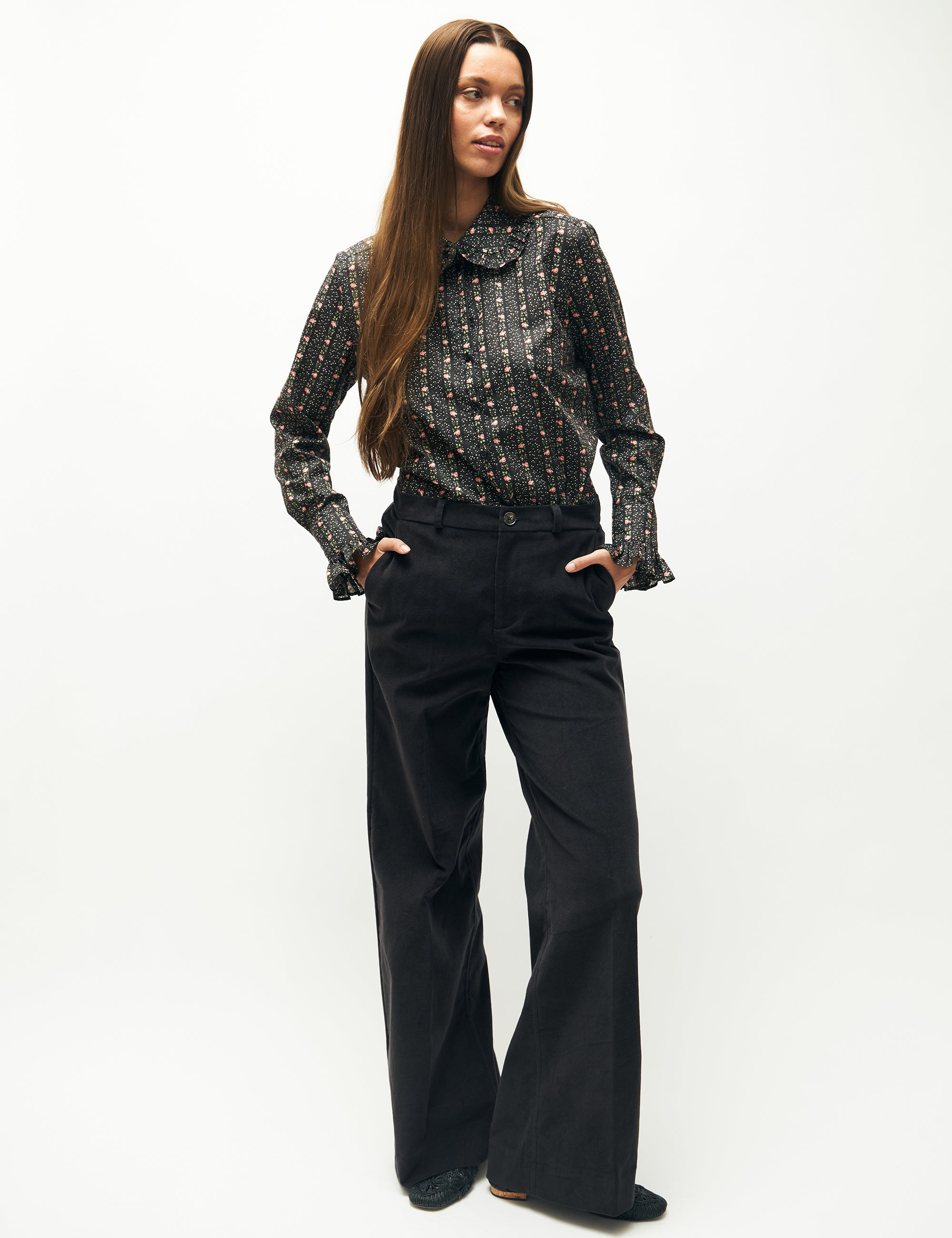 Woman in wide blue velvet trousers and floral striped long sleeved blouse with collar