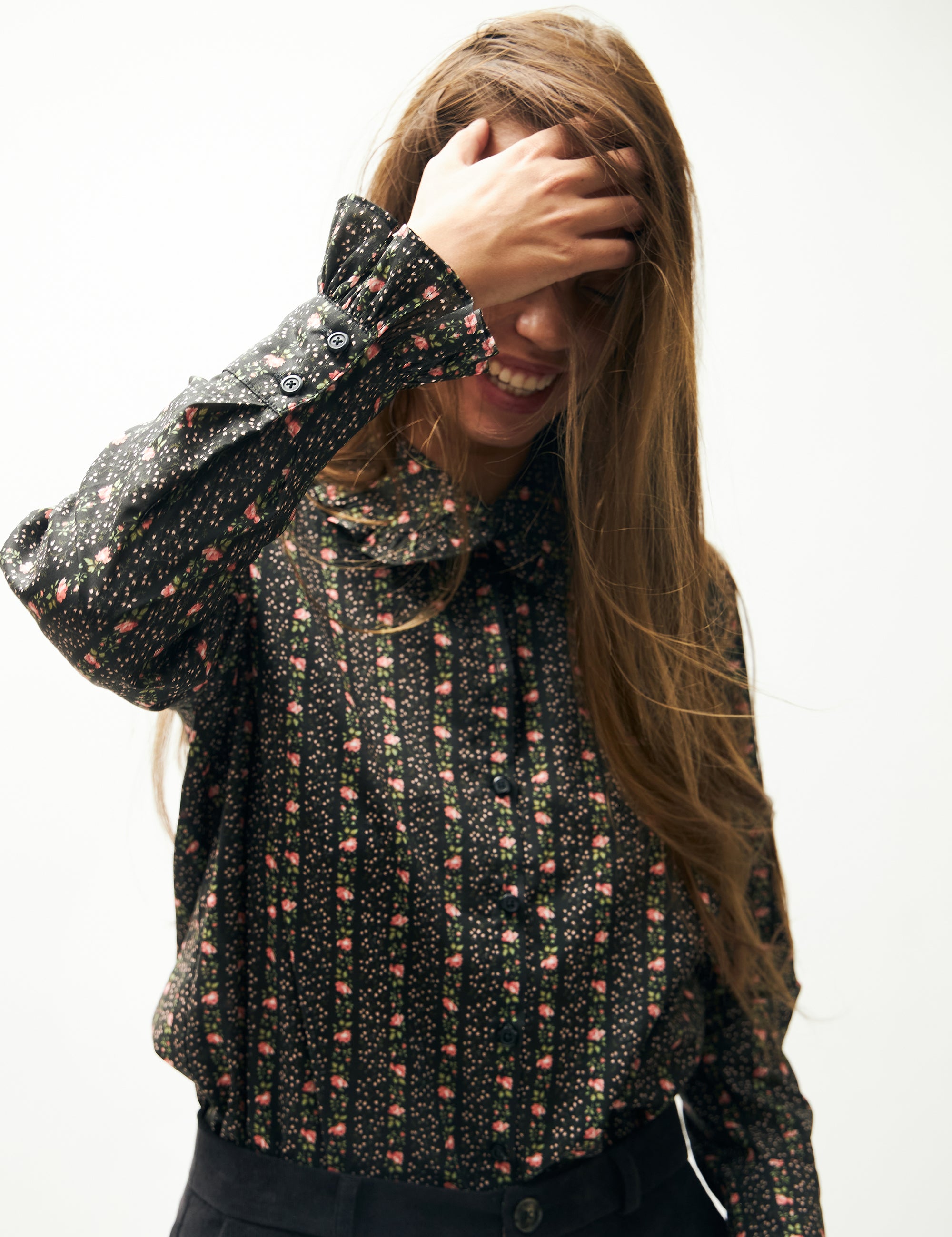 Woman in blue corduroy pants and long sleeved shirt with flower pattern and frills