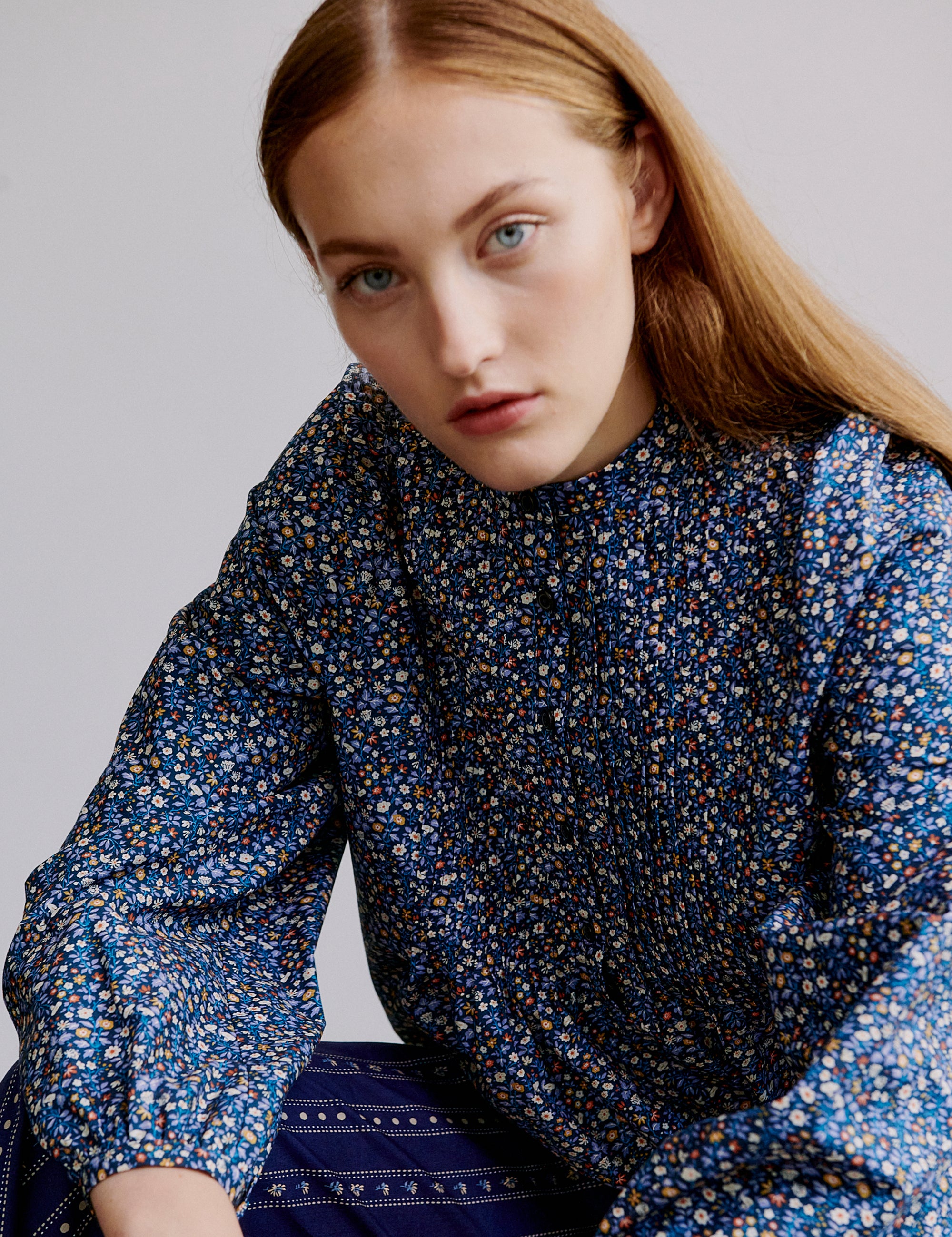 Woman wearing a blue floral blouse against a plain background