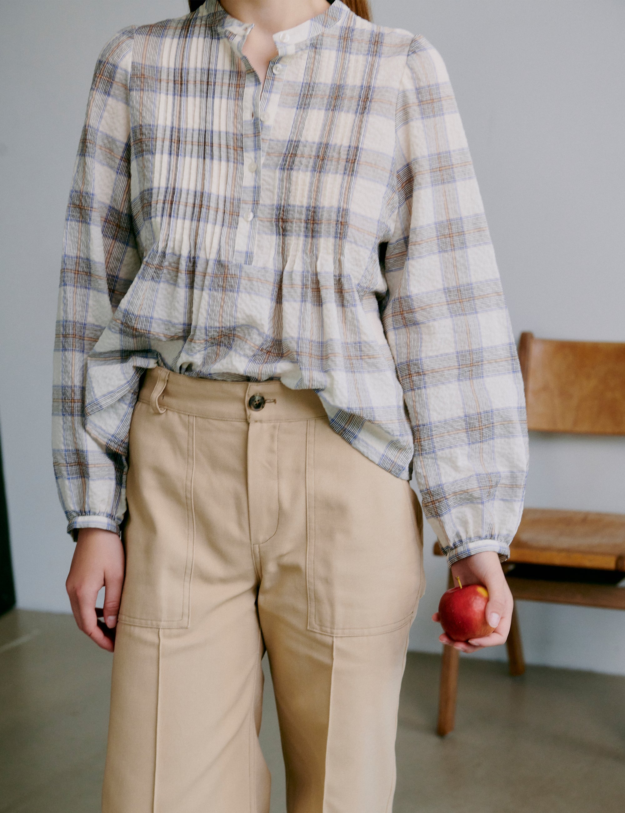 Woman wearing a check patterned grey and white shirt and beige pants