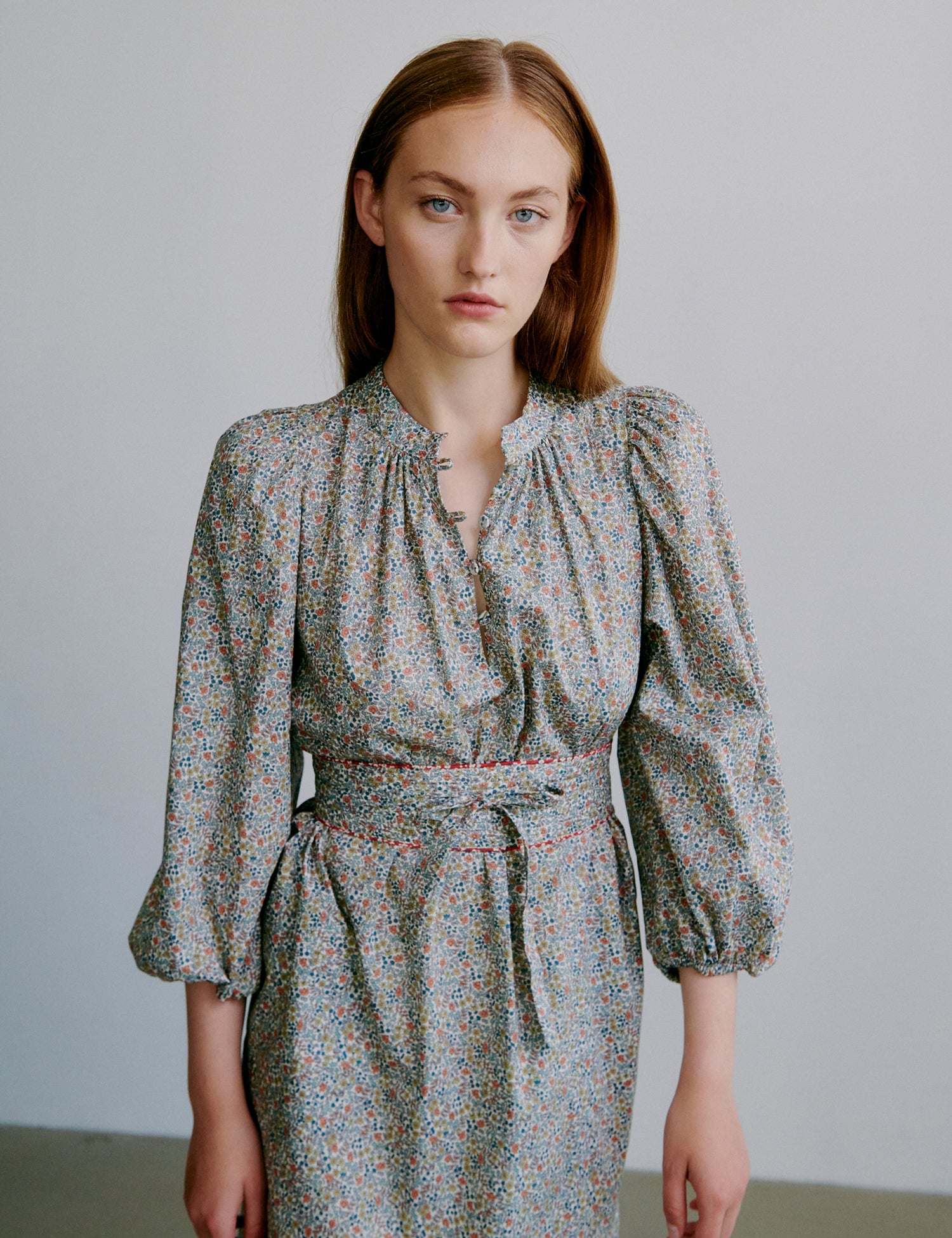 Woman wearing a short floral dress with puff sleeves and matching belt