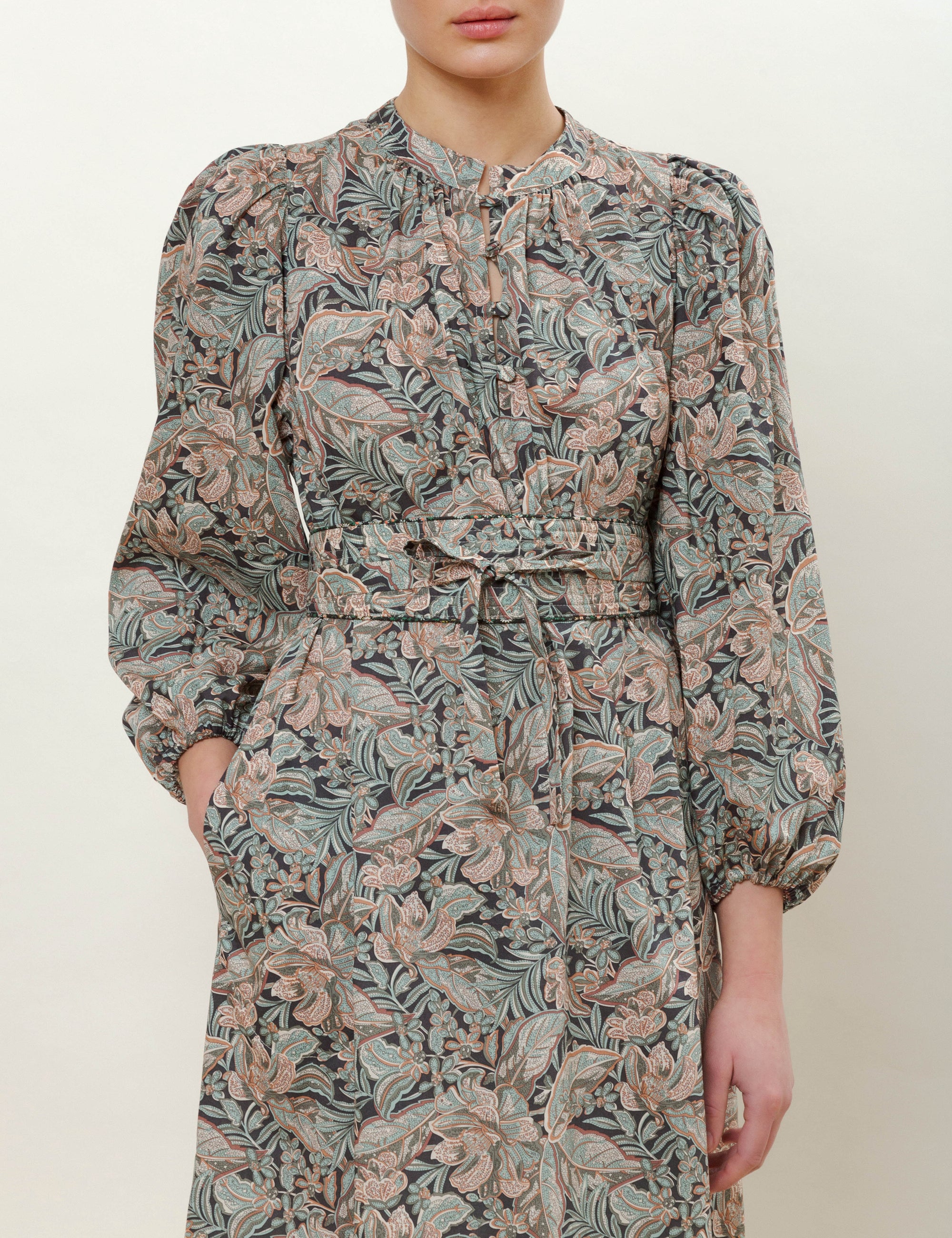 Woman in long sleeved paisley patterned dress with matching belt