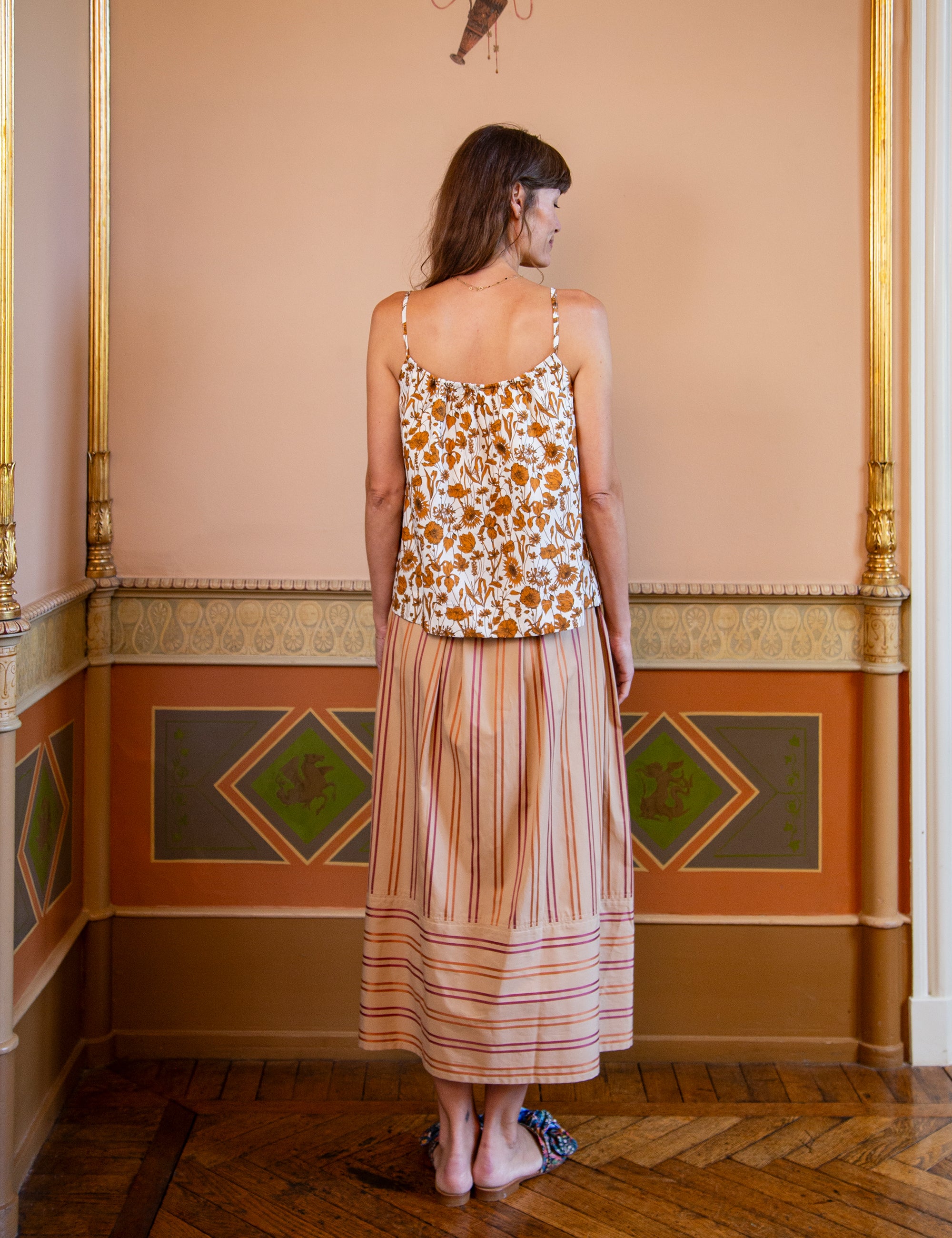 Woman wearing a floral patterned strap top and striped skirt