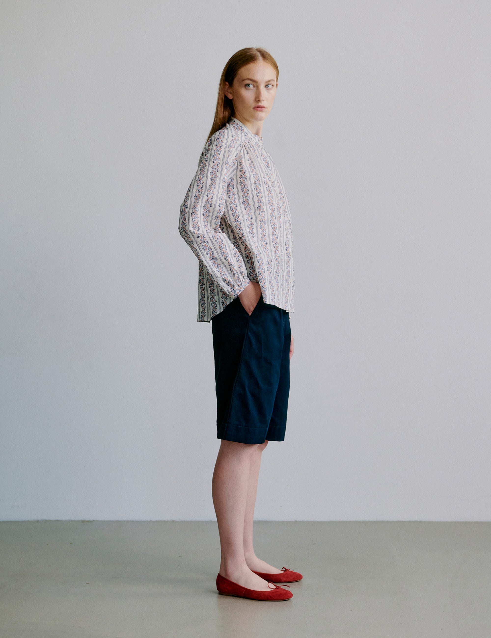 Woman wearing a long sleeve floral patterned blouse and navy shorts