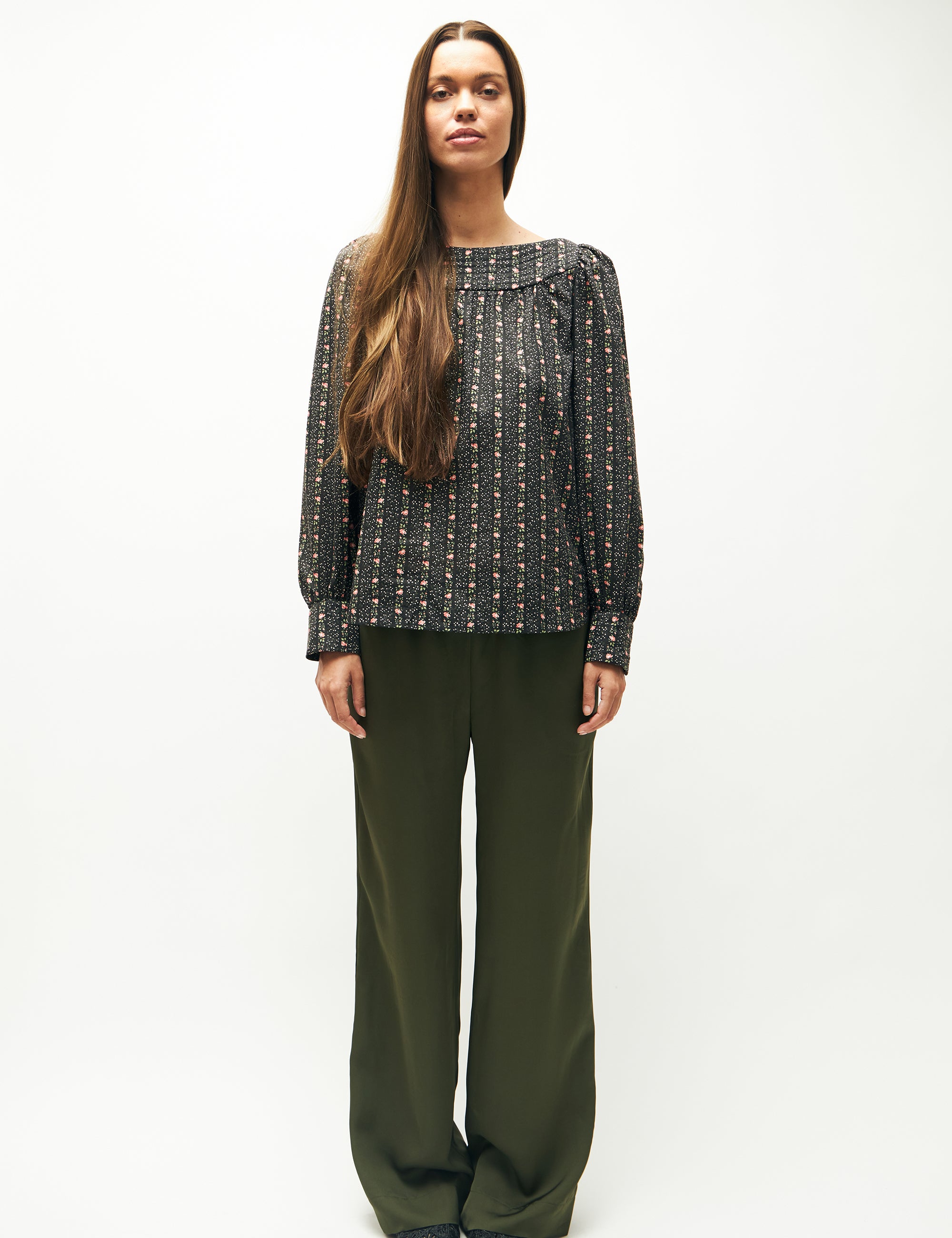 Woman in green pants and green flower patterned long-sleeved blouse