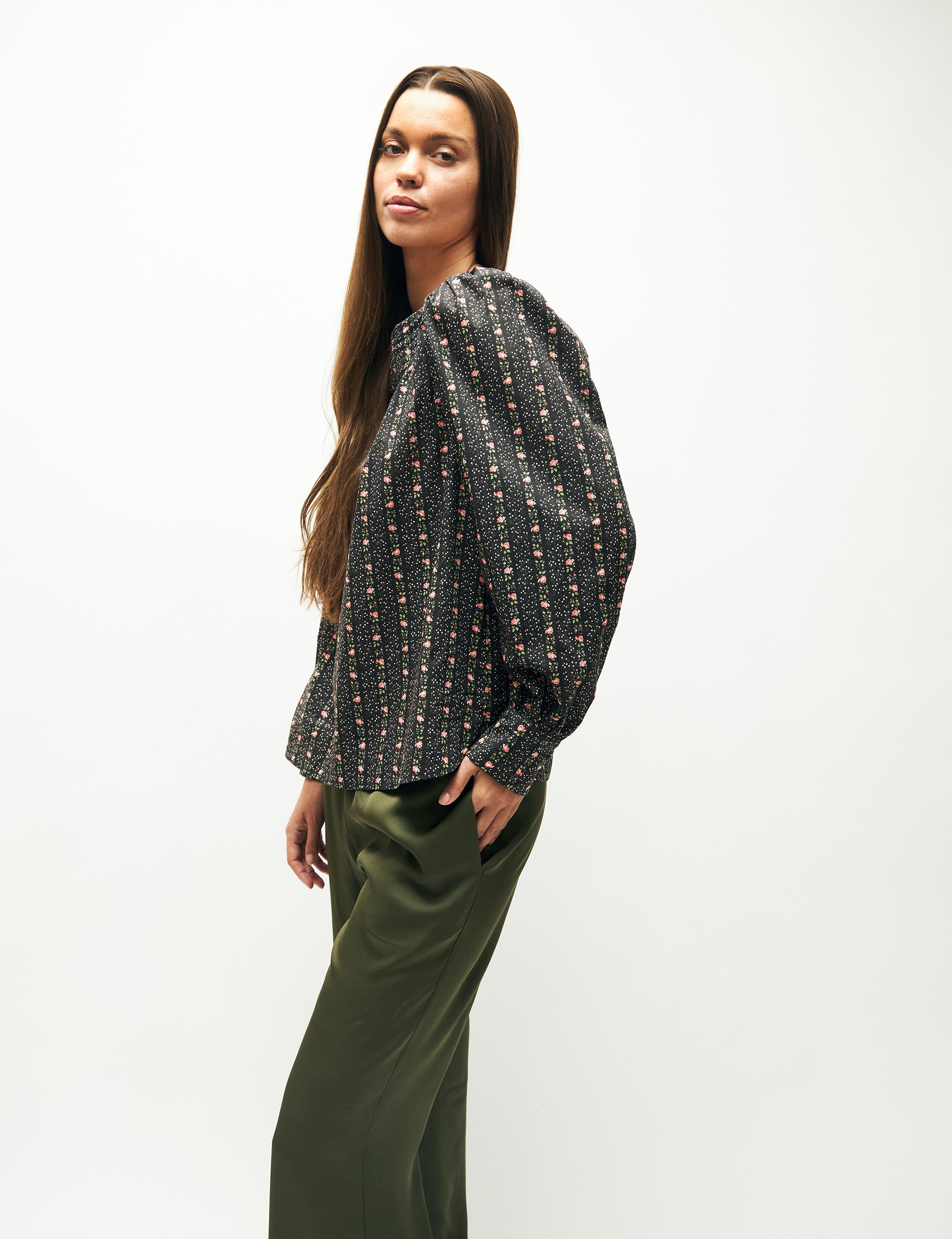 Woman in green pants and green flower patterned long-sleeved blouse