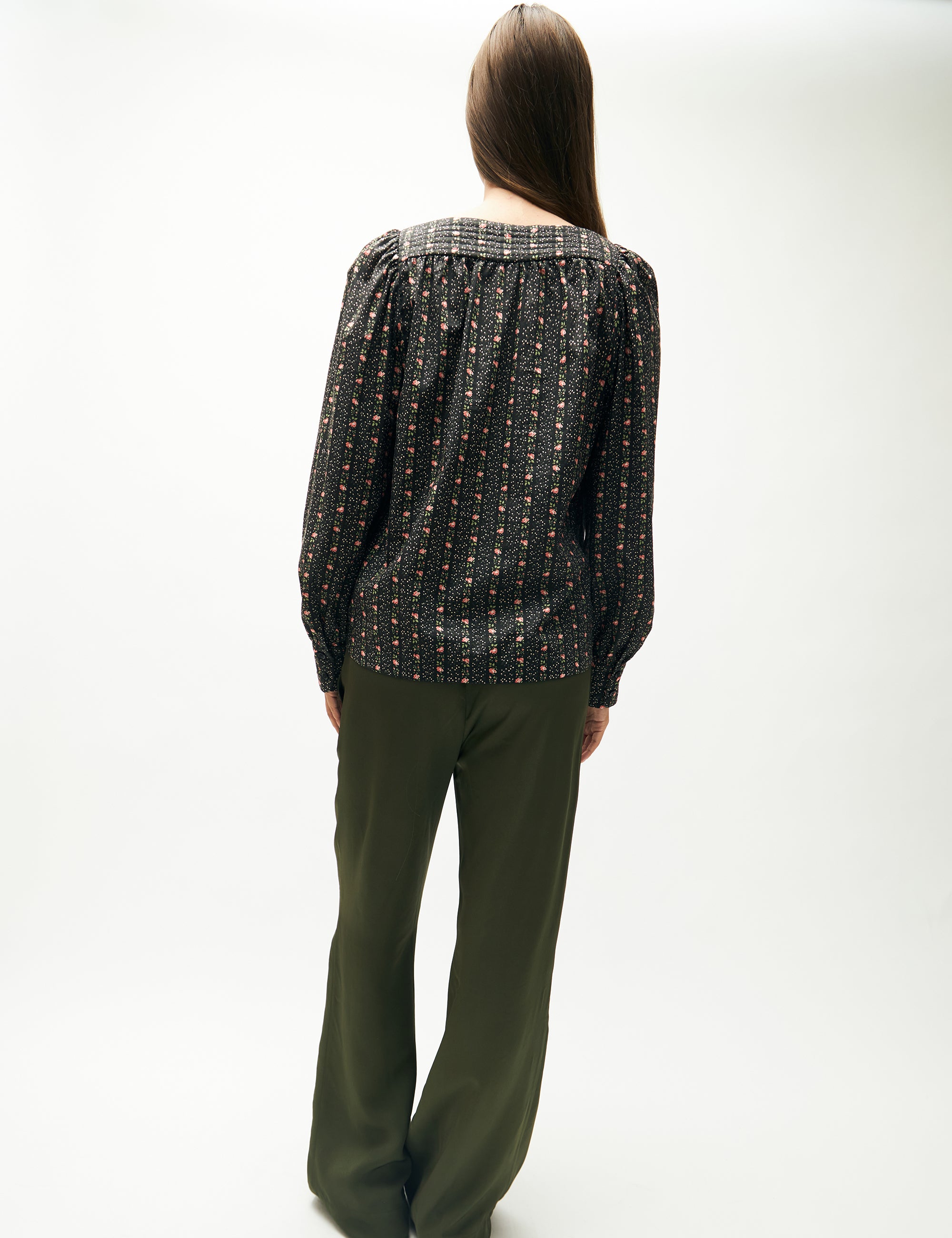 Woman in green pants and green flower patterned long-sleeved blouse