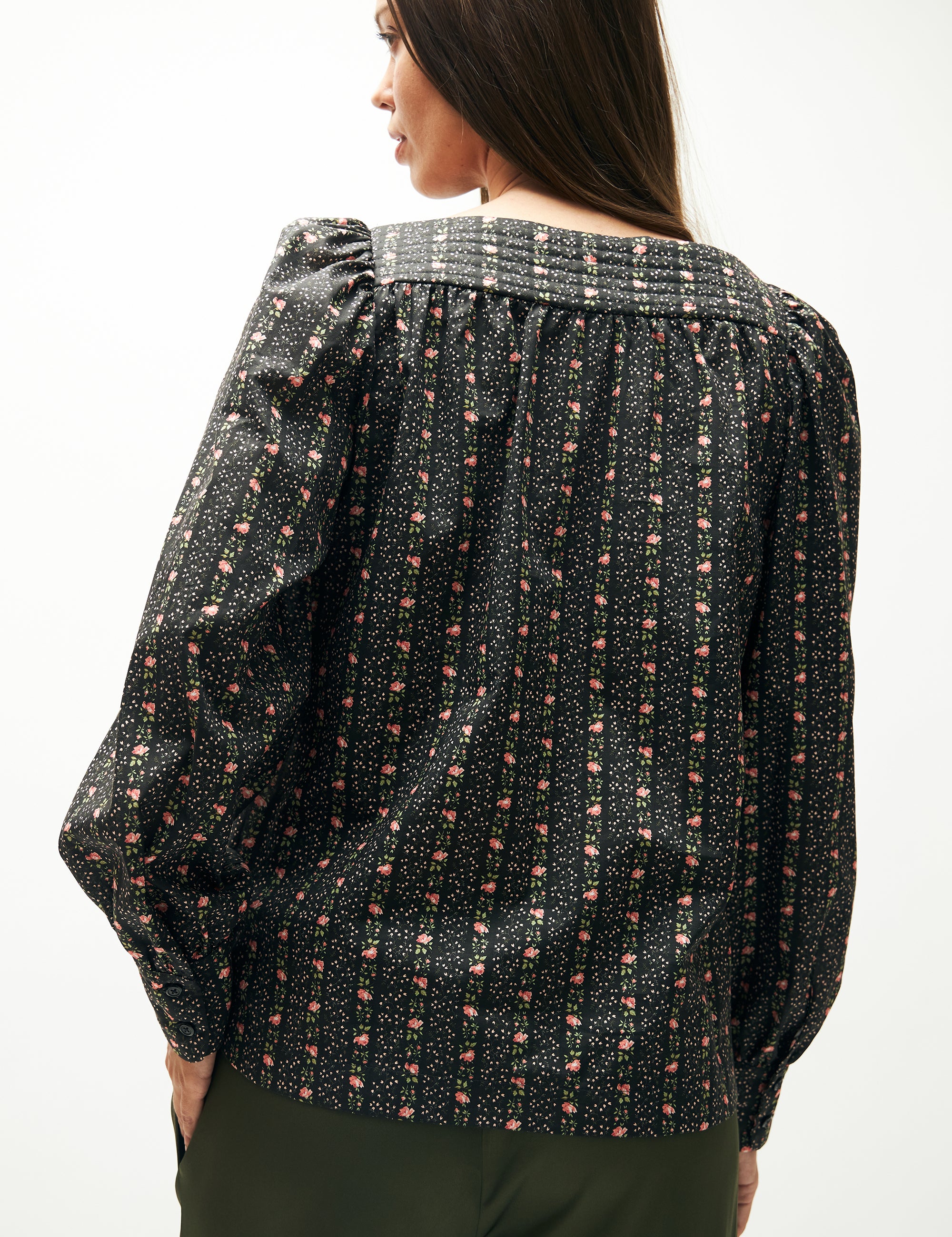 Woman in green pants and green flower patterned long-sleeved blouse