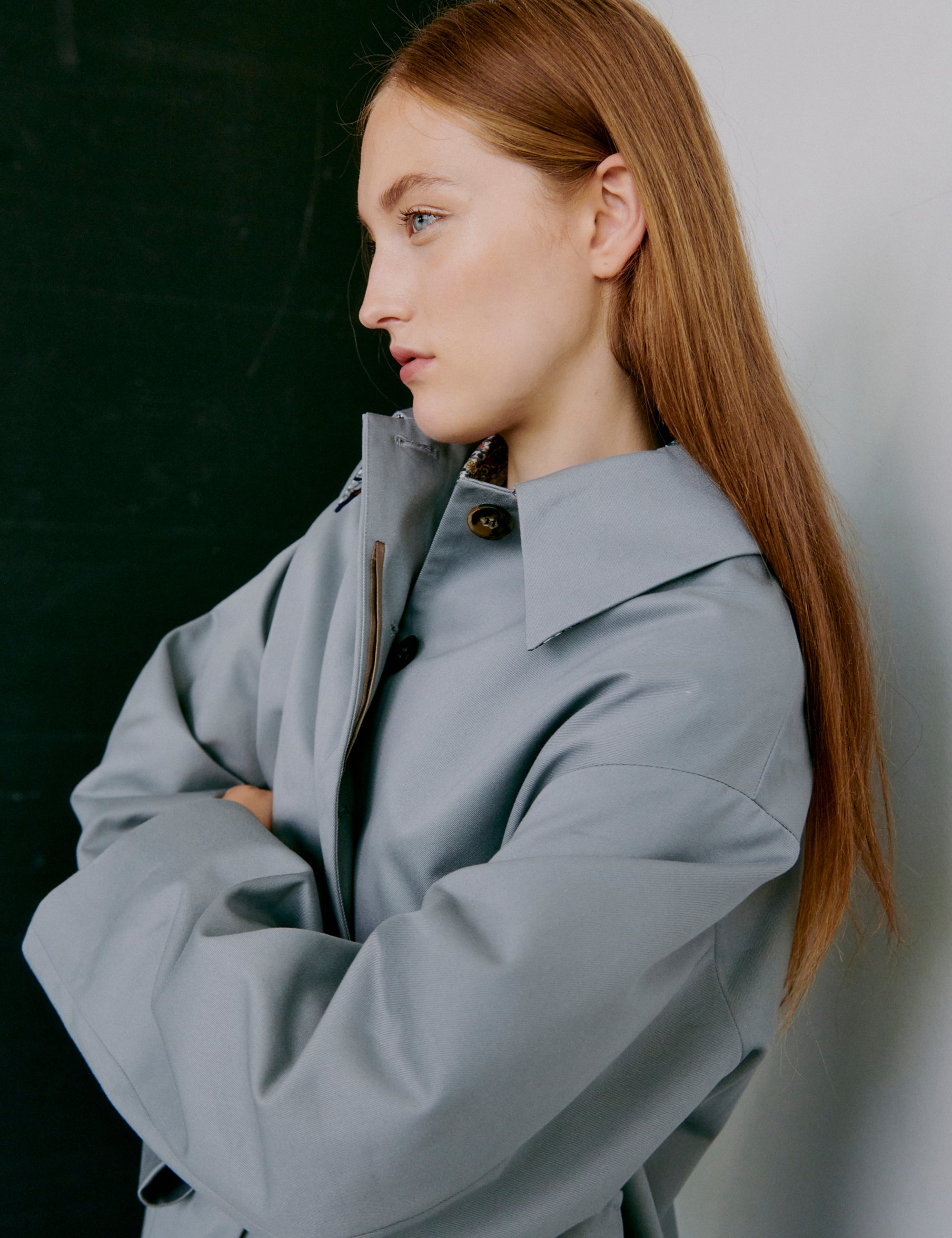 Woman wearing a light gray jacket against a dark background