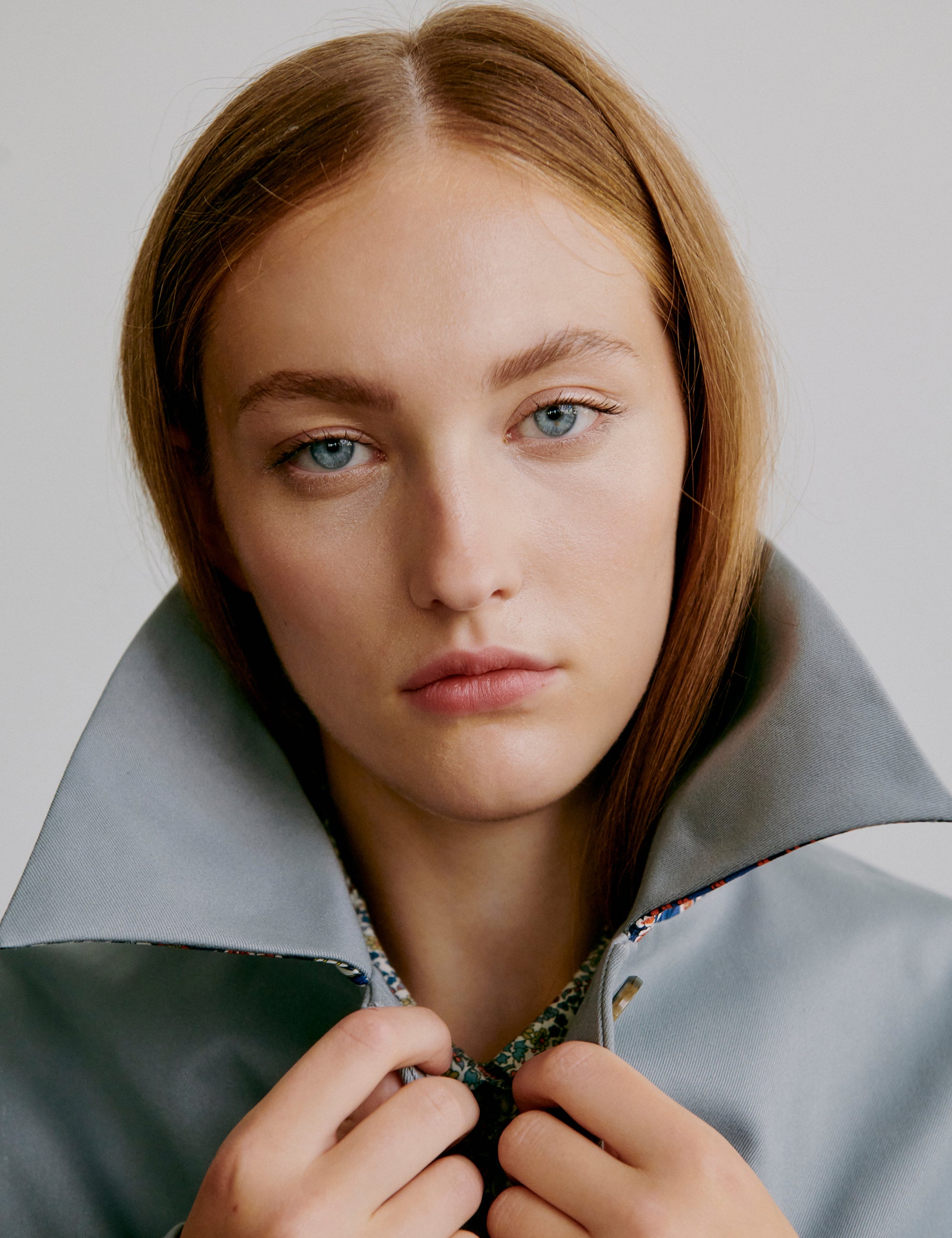 Woman wearing a gray jacket with large collar and flower patterned shirt beneath