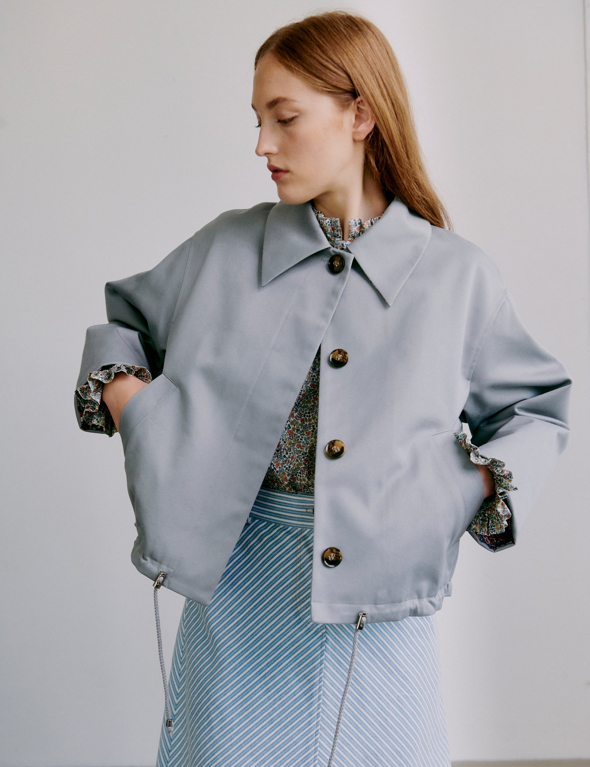 Woman wearing a light grey jacket and blue and white striped skirt