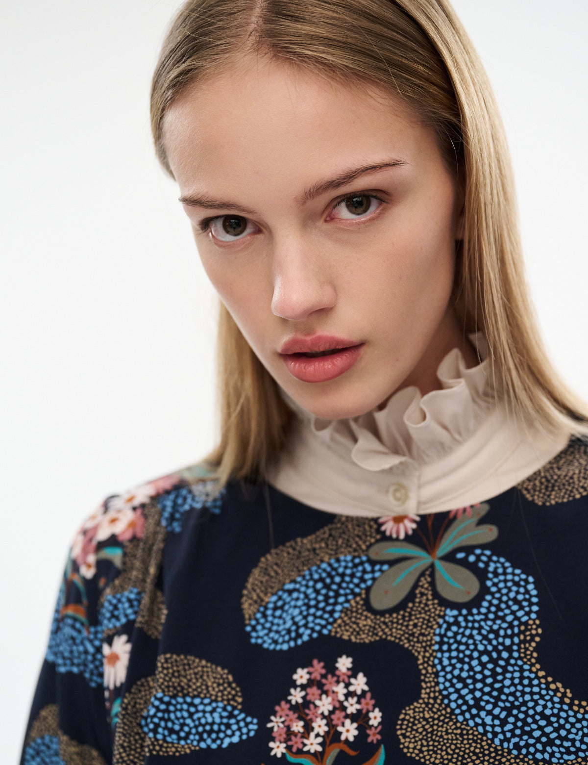 Printed blouse close-up with ruffled beige stand collar and dark navy butterfly floral print