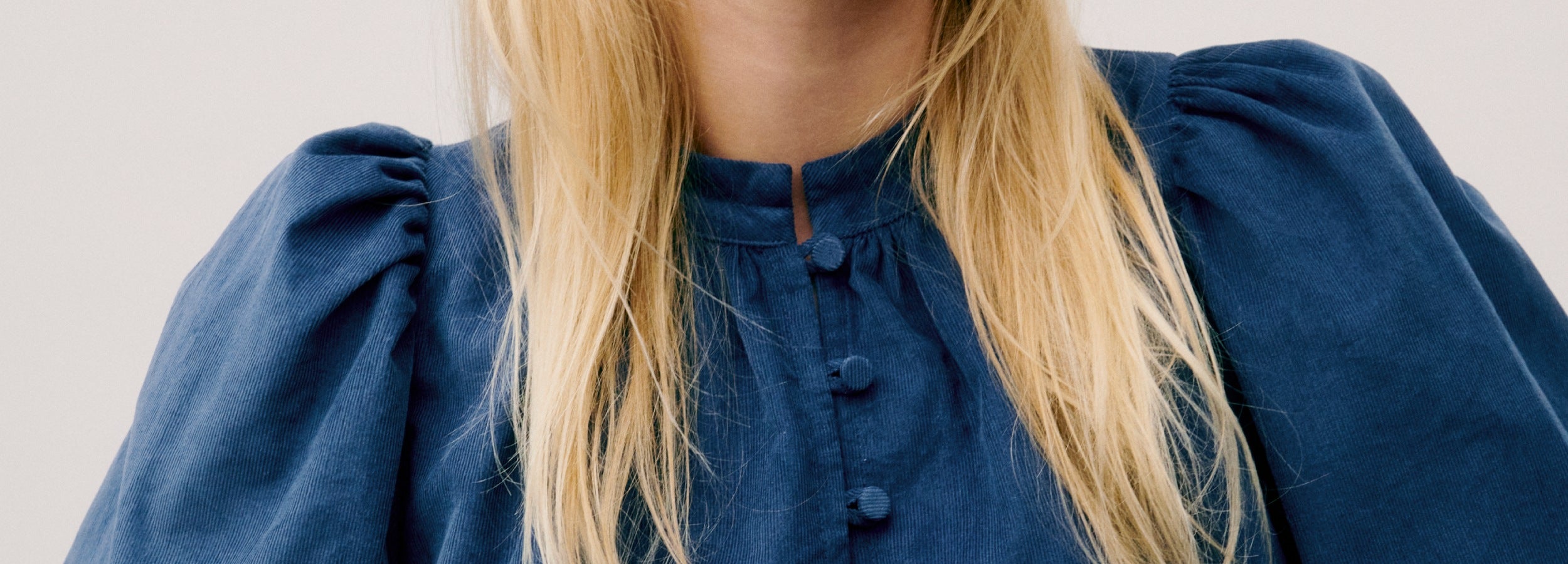 Woman in blue baby corduroy shirt with puff sleeves and covered buttons