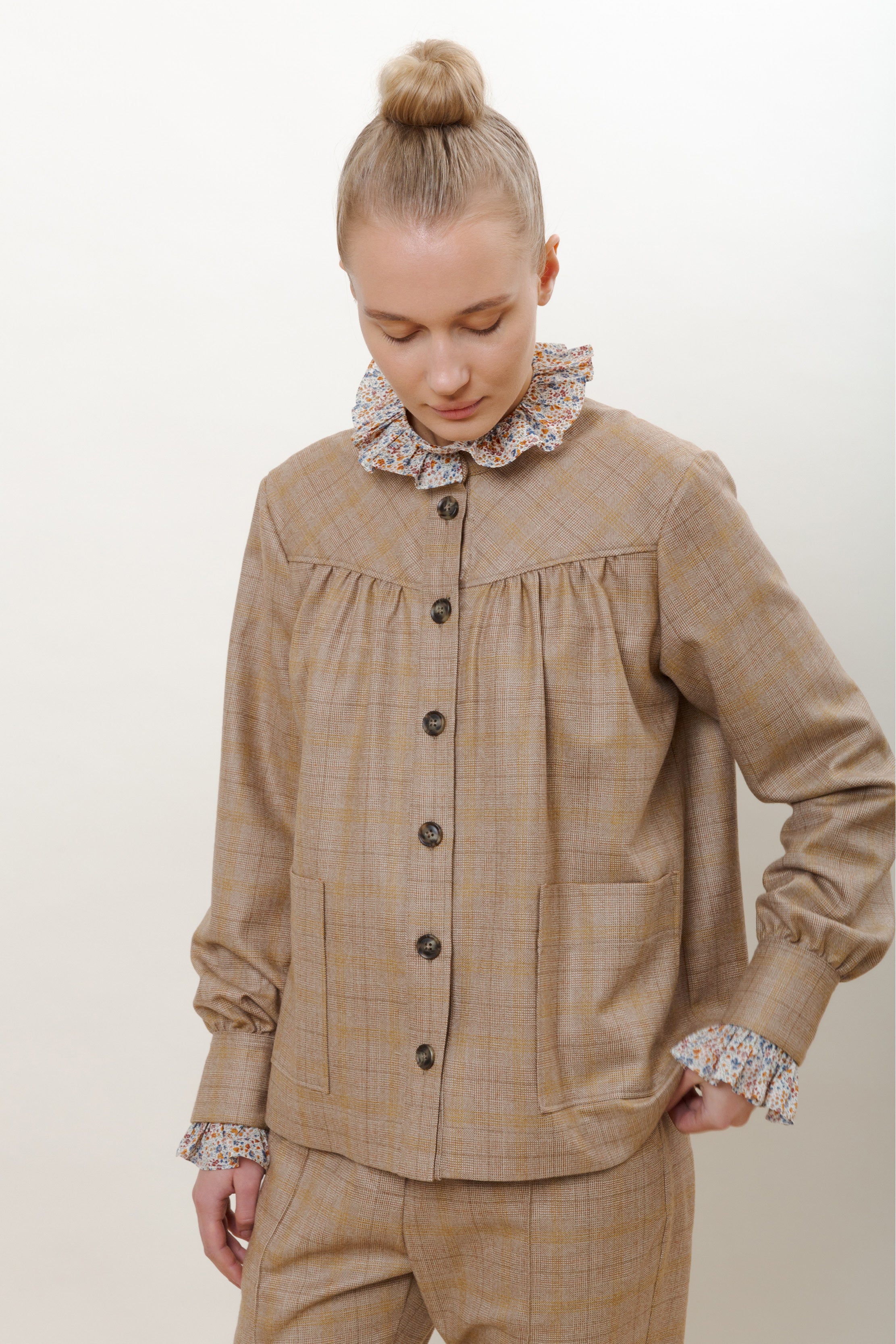 Woman in beige checked jacket and pants with Long sleeved women's shirt with flower pattern, ruffled collar and cuffs