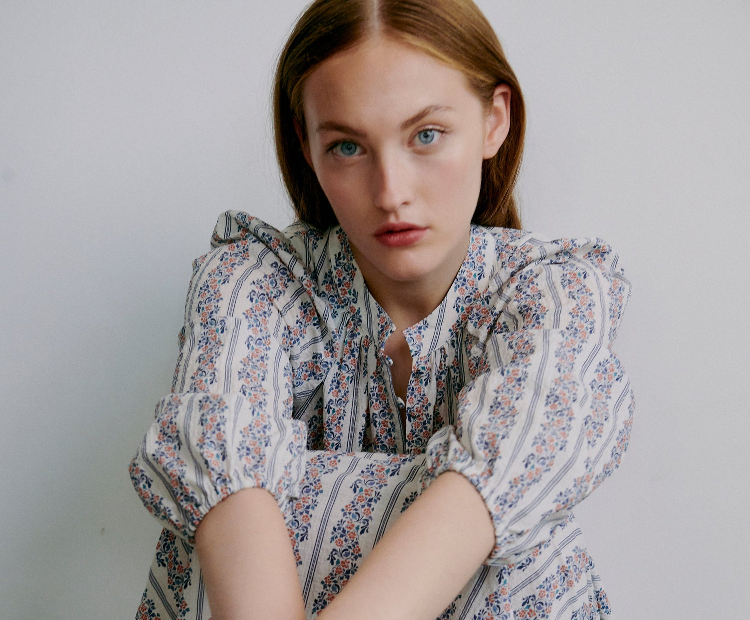 Woman wearing a floral blouse against a plain background