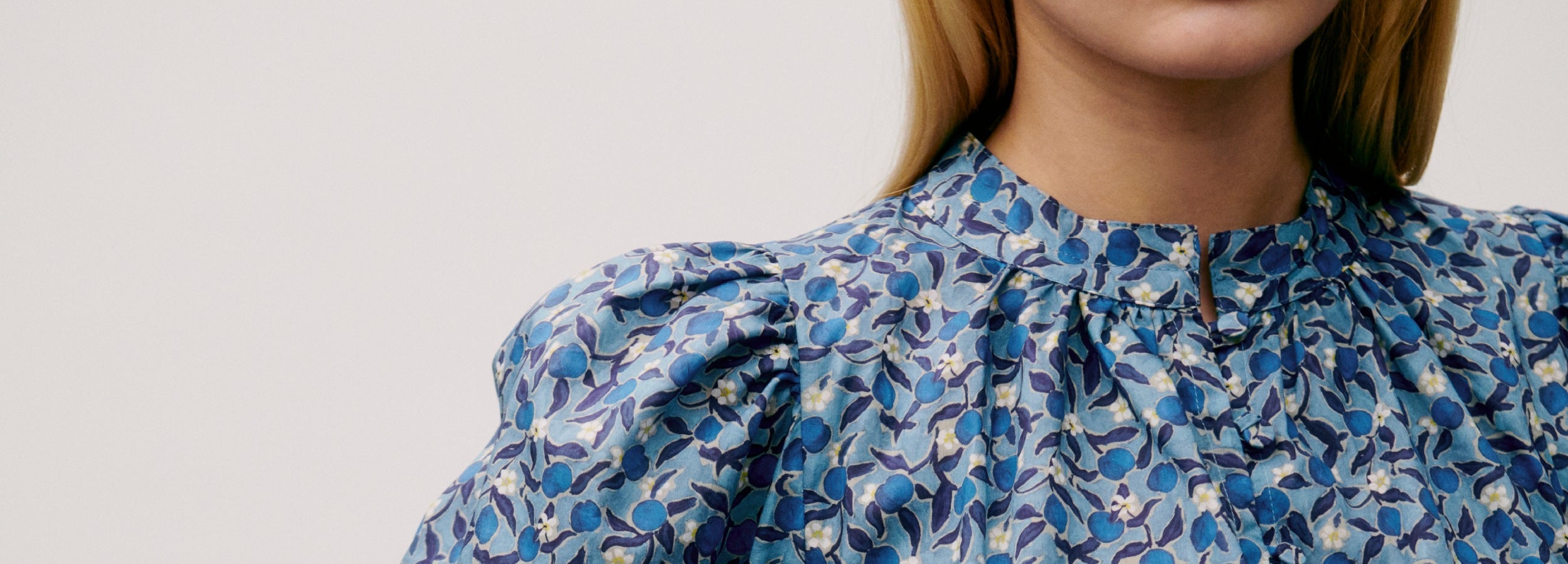 Close-up of a woman wearing a blue floral dress with buttons and puff sleeves
