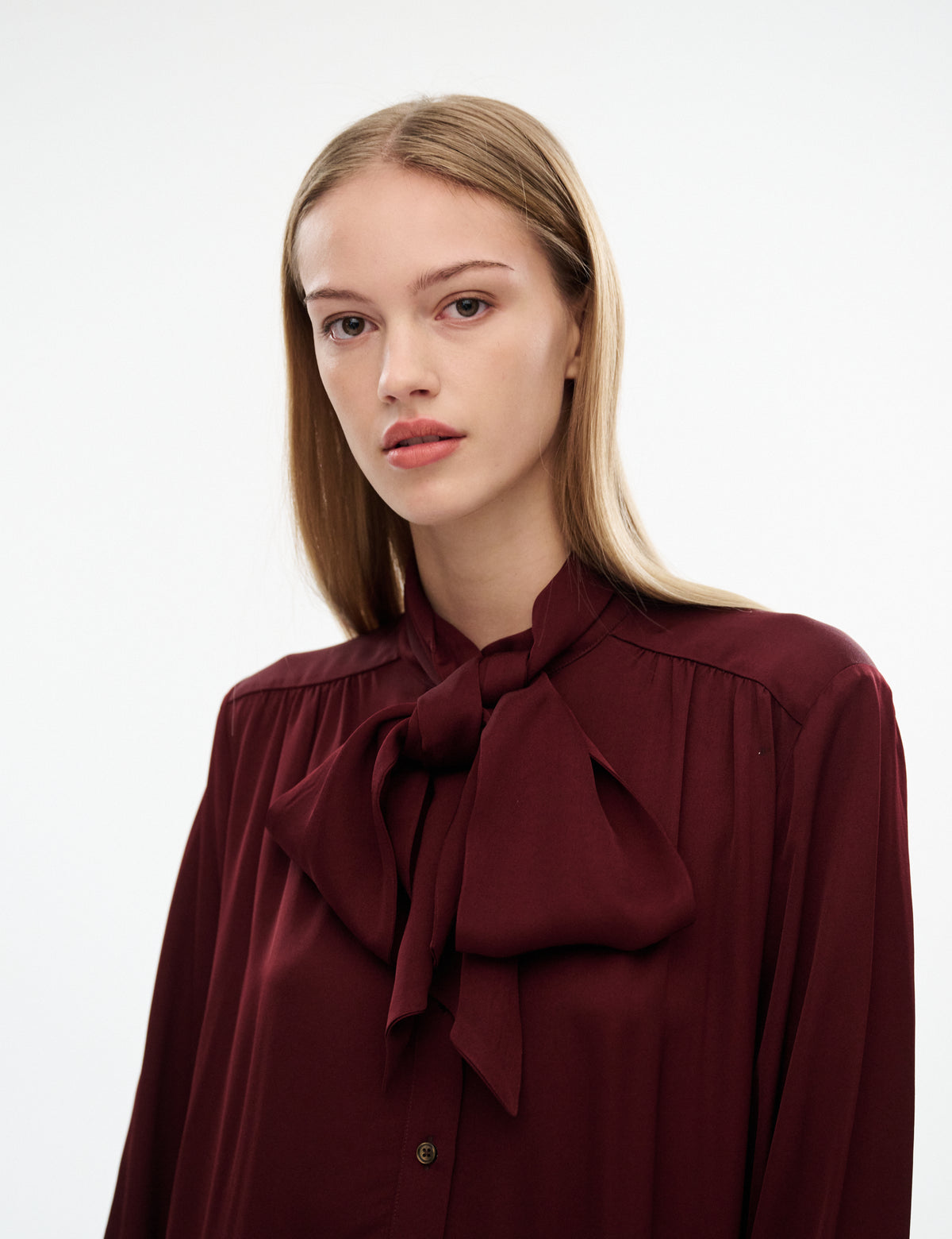 Burgundy dress close-up: tied bow collar with ruffled neckline and button placket
