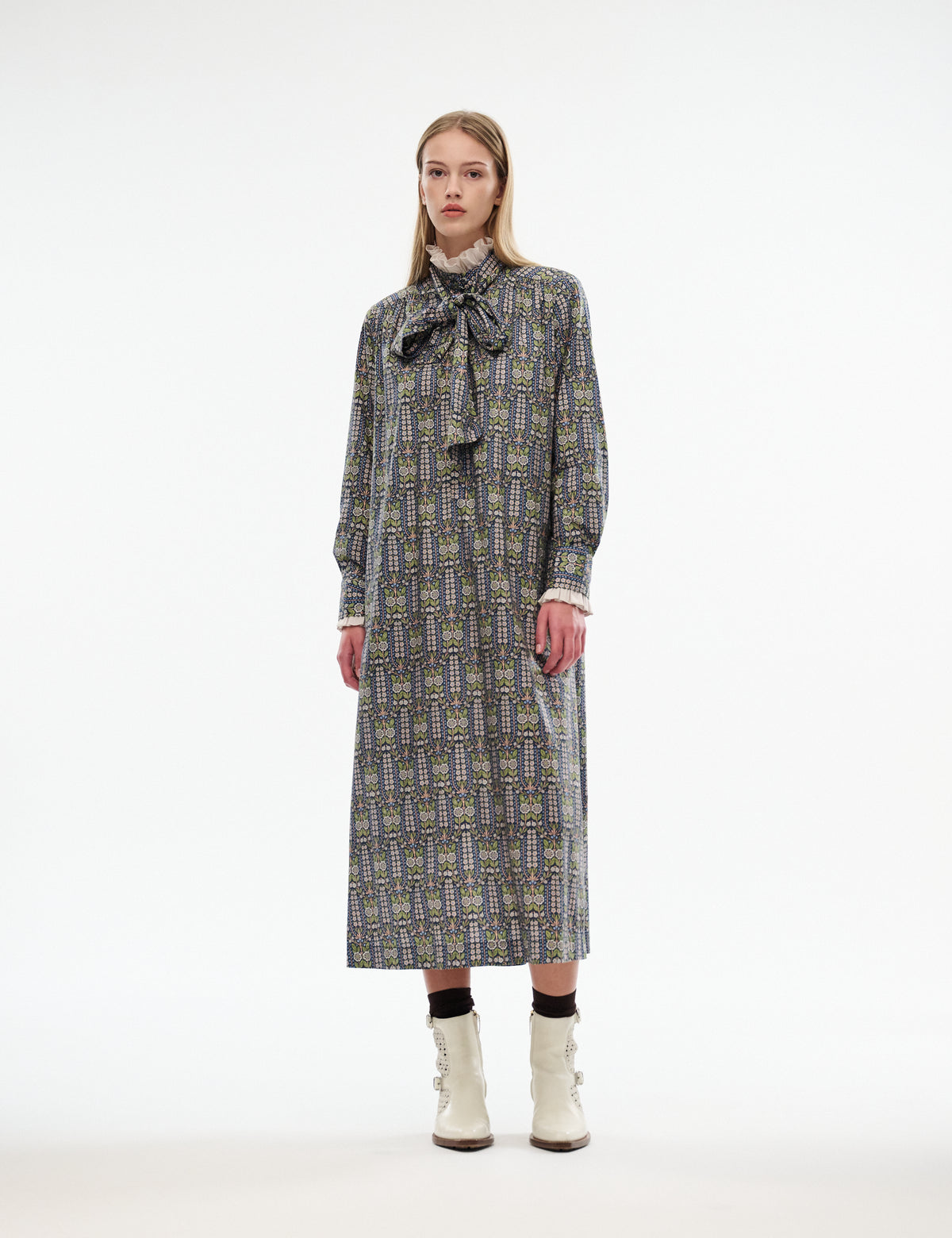 Mira dress front view with ruffled bow neckline and long cuffed sleeves; patterned dark fabric