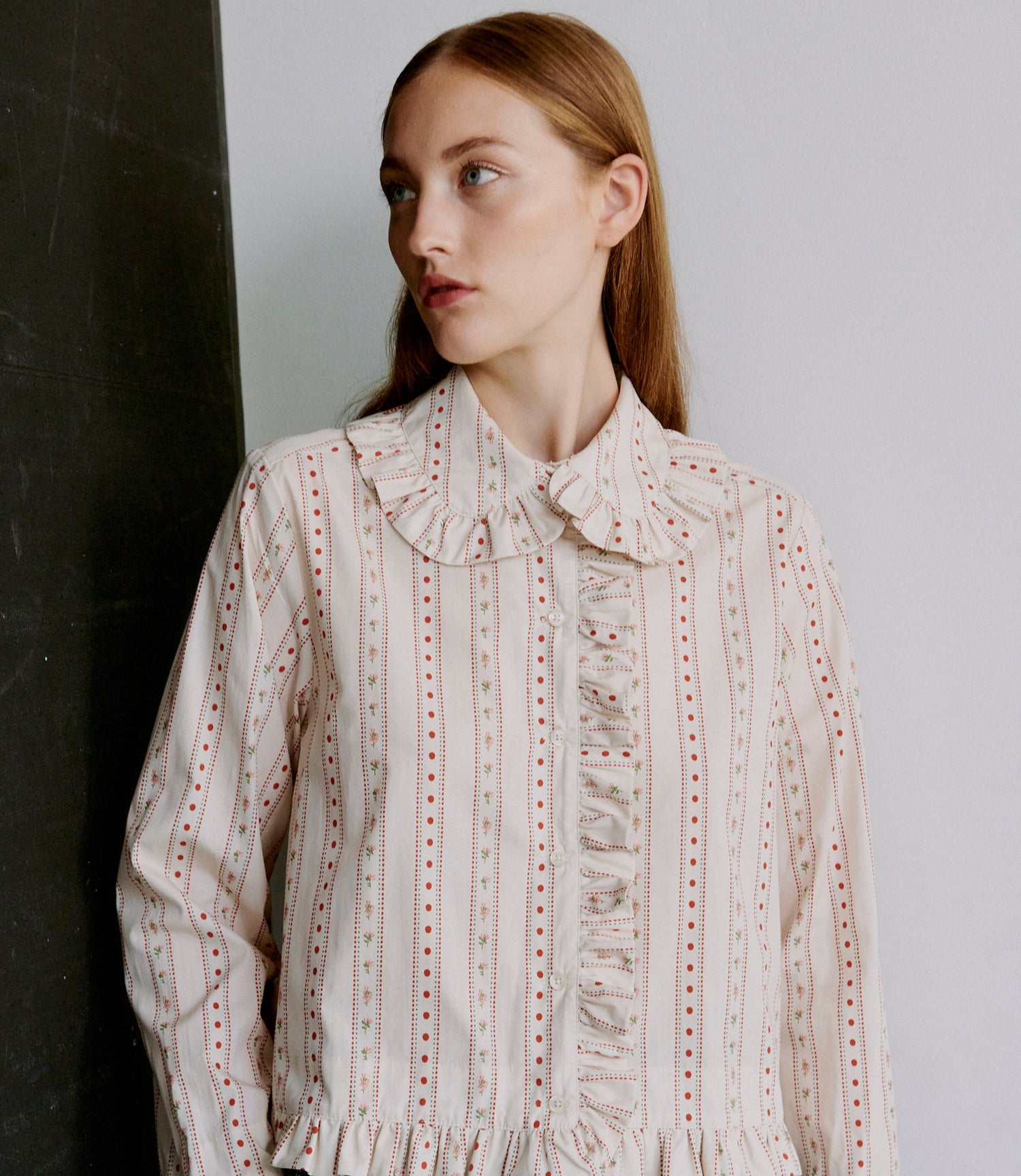 Woman wearing a patterned blouse against a plain background