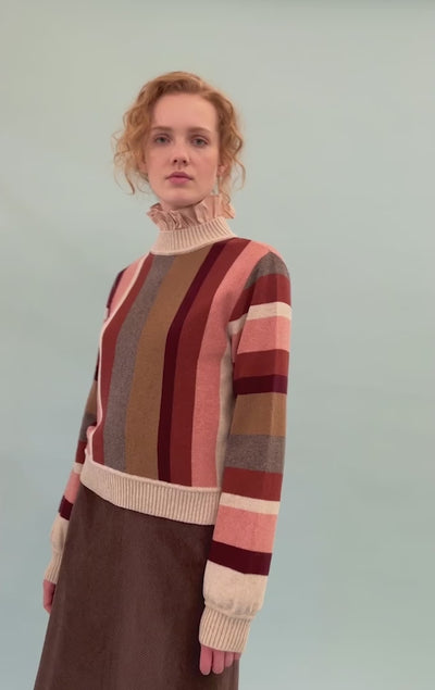 Woman in Striped wool pullover in pink, beige, brown and red, frilled pink blouse and brown skirt