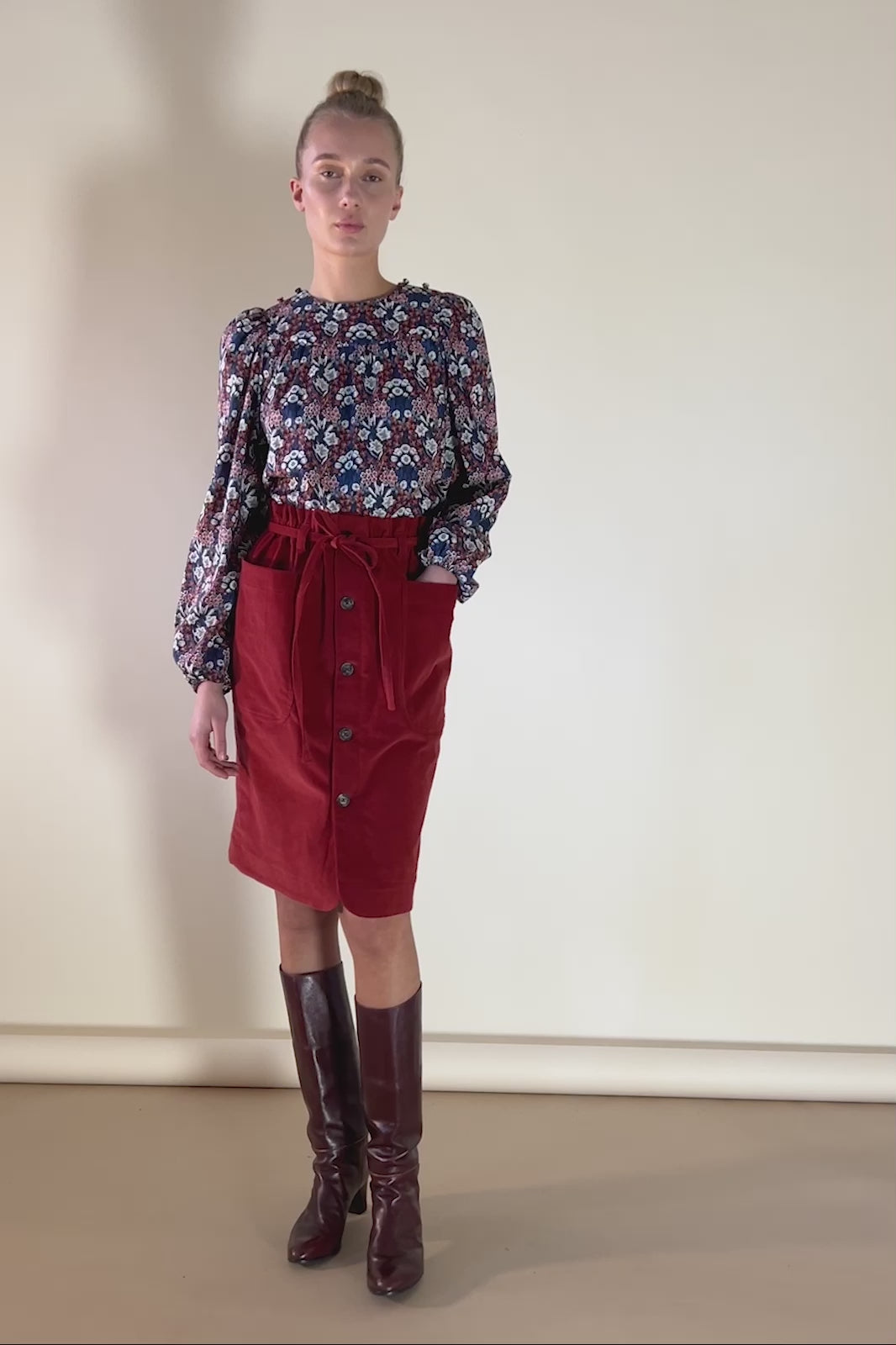 Woman in red baby cord skirt with buttons and Liberty cotton floral print shirt Primrose in red white and blue