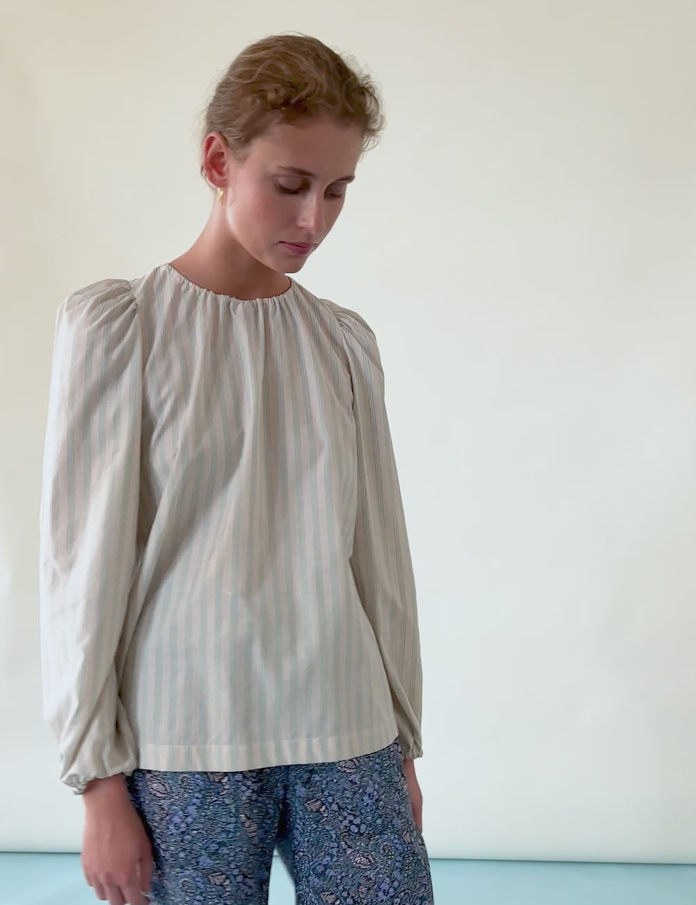 Woman in striped blouse with long sleeves and blue pants