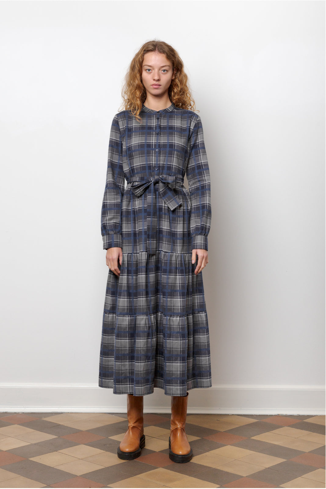 Woman in midi cotton dress with checks in blue and grey, long sleeves, buttons and belt