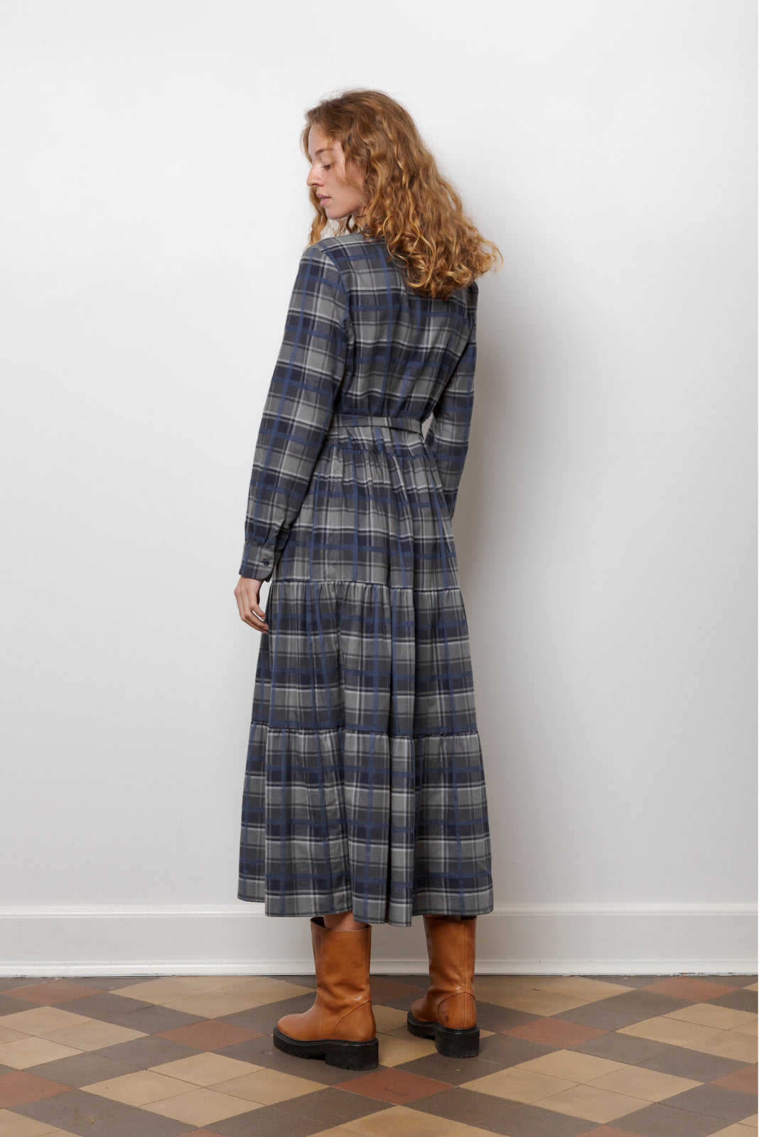 Woman in midi cotton dress with checks in blue and grey, long sleeves, buttons and belt