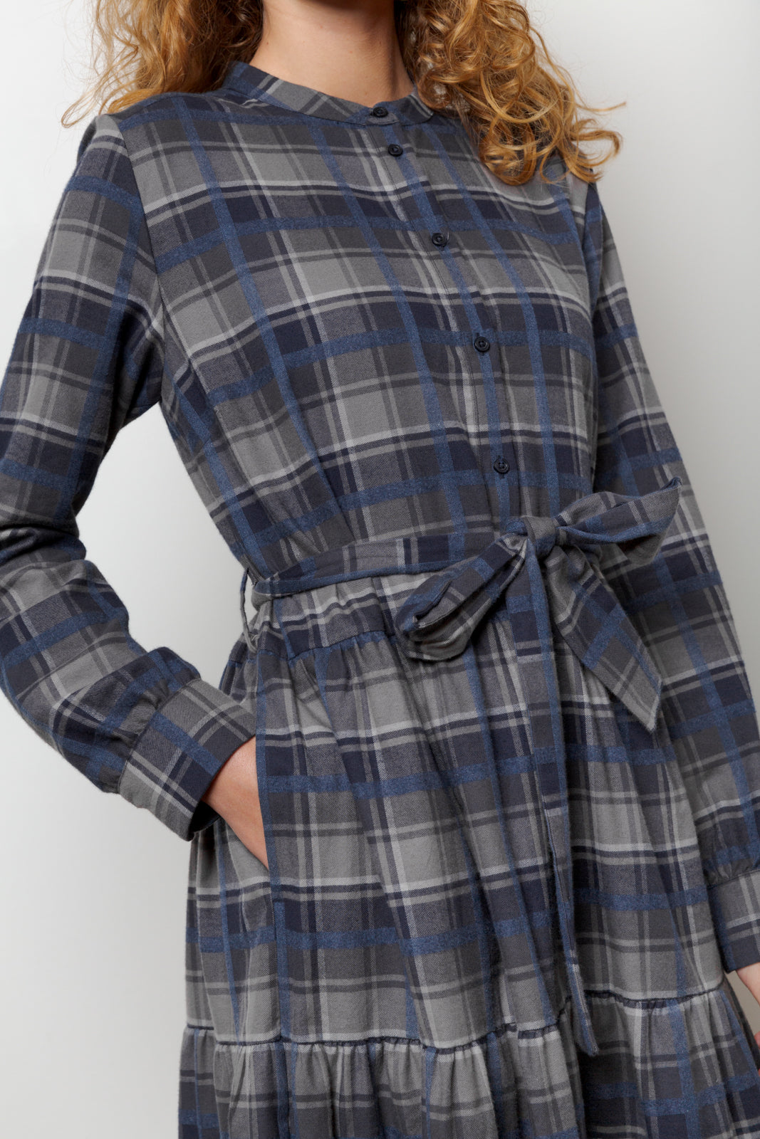 Woman in midi cotton dress with checks in blue and grey, long sleeves, buttons and belt