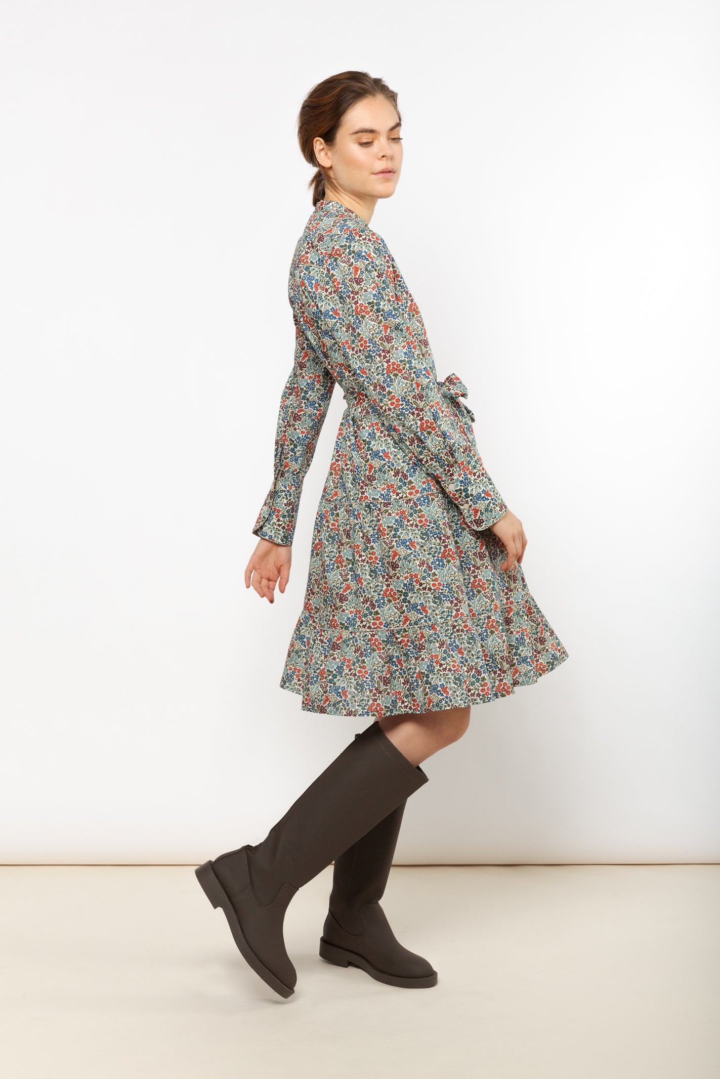 Woman in short dress with belt and flower pattern in red, blue and green