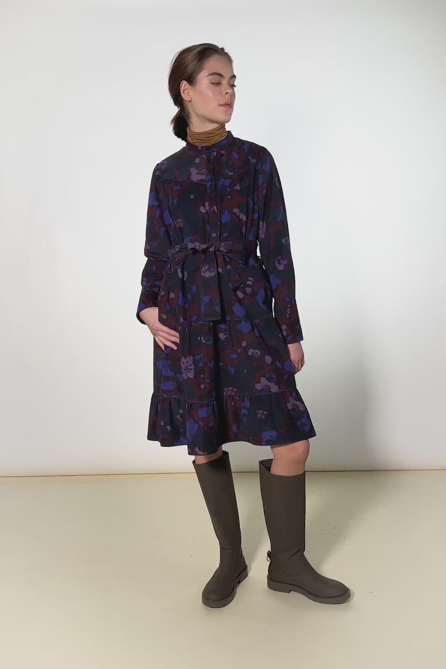 Woman in short dress with large flower pattern in red, blue and pink and belt